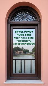 a window in a pink building with a sign on it at Eiffel Pondy in Pondicherry