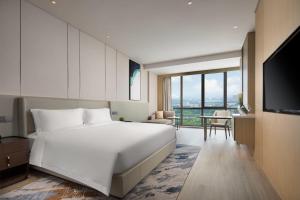 a bedroom with a large white bed and a table at Wyndham Shanghai Pudong in Shanghai +34 photos
