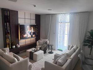 a living room with white couches and a tv at Alaziba view in ‘Udhaybah