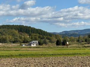 a house in a field with mountains in the background at Toma House in Tōma