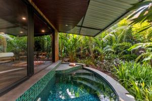 a swimming pool in a garden with a house at Eleve in Assagao
