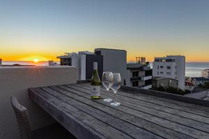 a bottle of wine and two glasses on a table with the sunset at Namaste in Cape Town
