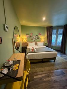 ein Schlafzimmer mit einem Bett, einem Tisch und einem Spiegel in der Unterkunft Hotel de Berne in Nizza