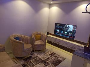 a living room with two chairs and a flat screen tv at Delight 1 Bedroom Apartment - Off Awolowo Road Ikeja in Ikeja