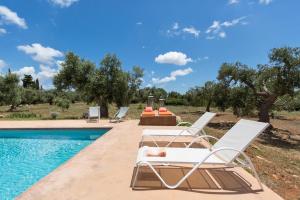 einen Pool mit 2 Liegestühlen und einem Tisch neben einem Pool in der Unterkunft Villa Rosalore' by BarbarHouse in Ugento