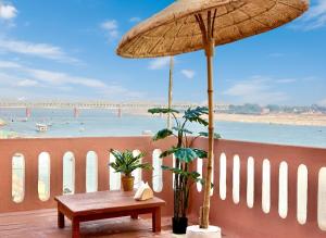 a table with a umbrella and a bench on a balcony at Vintage River Homestay in Varanasi