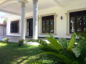 a house with columns and green grass at Hill House Rest in Mirissa