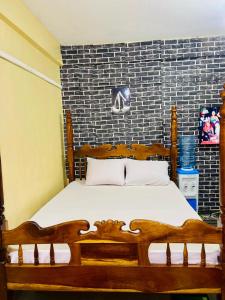 a bedroom with a wooden bed and a brick wall at Serenity Suites Studio in Busia