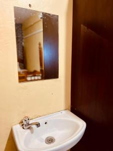 a white sink in a bathroom with a mirror at Serenity Suites Studio in Busia +3 photos