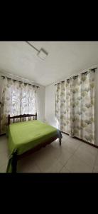a bedroom with a green bed and a window at Perle rare Lodge in Diamond Island