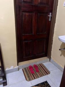 a pair of red shoes on a rug in front of a door at Serenity Suites Studio in Busia