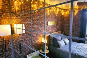 a room with a brick wall with a bed and lights at L atelier des jeux in Beauvais