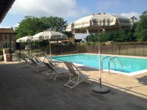 uma piscina com espreguiçadeiras e guarda-sóis ao lado de uma piscina em Villa Gourmet em Orentano