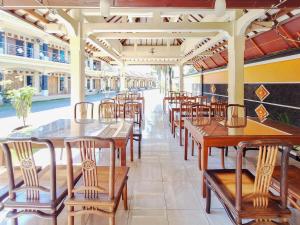 an empty restaurant with wooden tables and chairs at Hotel Syariah Milik Kita Borobudur Mitra RedDoorz in Borobudur +32 photos