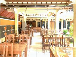 an empty restaurant with wooden tables and chairs at Hotel Syariah Milik Kita Borobudur Mitra RedDoorz in Borobudur
