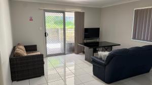 a living room with a couch and a table and a television at 4 bedrooms with queen sized bed each room in Riverview
