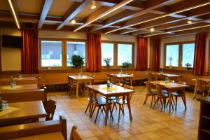 a restaurant with wooden tables and chairs and windows at Jugendpension Müllauerhof in Saalbach Hinterglemm