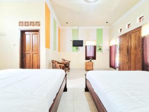 a bedroom with two beds and a dining room at Hotel Syariah Milik Kita Borobudur Mitra RedDoorz in Borobudur