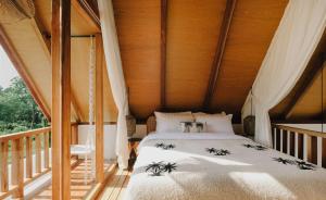a bed in a room with a wooden ceiling at Palm Valley Loft in Kuta Lombok