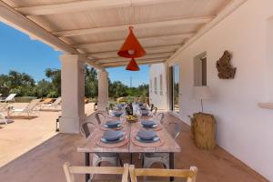 - une longue table en bois avec des chaises sur la terrasse dans l'établissement Villa Rosalore' by BarbarHouse, à Ugento