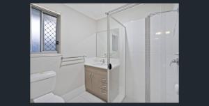 a white bathroom with a shower and a sink at 4 bedrooms with queen sized bed each room in Riverview