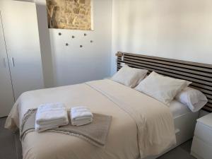 a bedroom with a white bed with towels on it at CasaElbarranko in Arcos de la Frontera