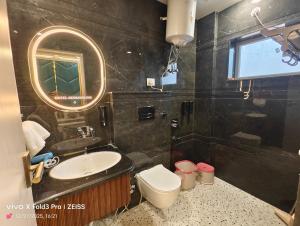 a bathroom with a sink and a toilet and a mirror at Hotel Akshansh Inn in Agra