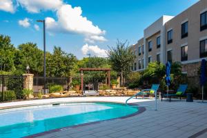 a swimming pool with two chairs next to a building at Hampton Inn & Suites College Station in College Station
