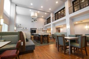 a restaurant with tables and chairs and a kitchen at Hampton Inn & Suites College Station in College Station