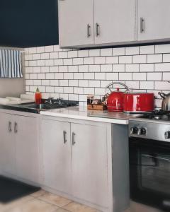 a kitchen with white cabinets and red pots and pans at Summerville Place in Addo