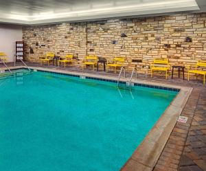 a swimming pool with chairs and tables and a brick wall at Hampton Inn Pigeon Forge in Pigeon Forge