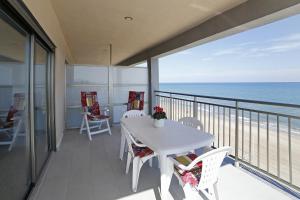 balcón con mesa, sillas y vistas al océano en Apartamento frente al mar, en Bellreguart