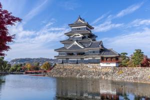 a large building sitting on the side of a lake at CatNook 猫ちぐら in Matsumoto