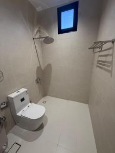 a white bathroom with a toilet and a window at نسيم العلا - Naseem AlUla in Al-ʿUla