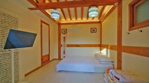 a small room with a bed and a tv at Hanok Onew in Jeonju