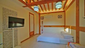 a bedroom with a bed and a flat screen tv at Hanok Onew in Jeonju