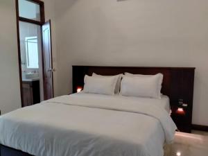 a bedroom with a large bed with white sheets and pillows at Dilvilla in Nikawatawana