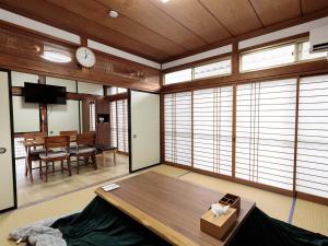 a living room with a table and a clock on the wall at わのおうち善 in Nitanzawa