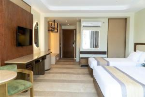 a hotel room with two beds and a desk at Coron Westown Resort Premier in Sampong