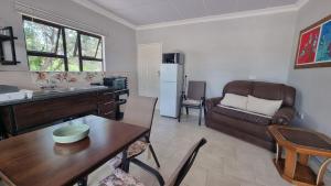 a kitchen and living room with a table and a couch at Maggie's Farm Stay in Khanzi