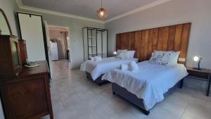 a bedroom with two beds and a wooden headboard at Maggie's Farm Stay in Khanzi