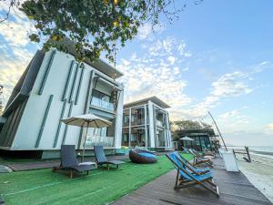 a house on the beach with chairs and an umbrella at Leamsai Beach Resort in Suratthani