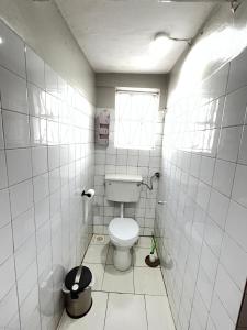 a white bathroom with a toilet and a window at Spacious one bedroom Bangalow -8E3 in Kampala +7 photos