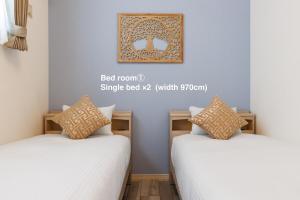 two beds in a room with a picture on the wall at Katan A in Yamada