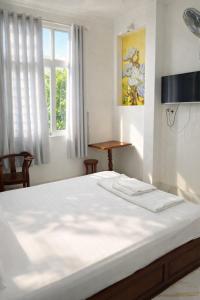 a bedroom with a large white bed with a window at Sao Mai Hotel Can Tho in Can Tho