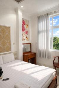 a white bedroom with a bed and a window at Sao Mai Hotel Can Tho in Can Tho