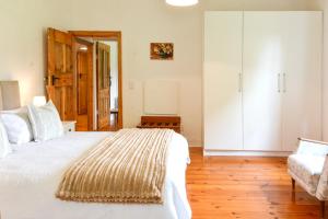 a bedroom with a large white bed and a couch at Burnside Lodge in Balgowan