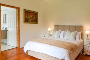 a bedroom with a large bed with white pillows at Burnside Lodge in Balgowan +49 photos