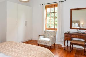 a bedroom with a bed and a desk and a chair at Burnside Lodge in Balgowan