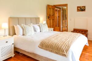 a bedroom with a large white bed with white pillows at Burnside Lodge in Balgowan
